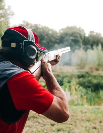 hunter shoots with a shotgun on a target in special clothes and headphones